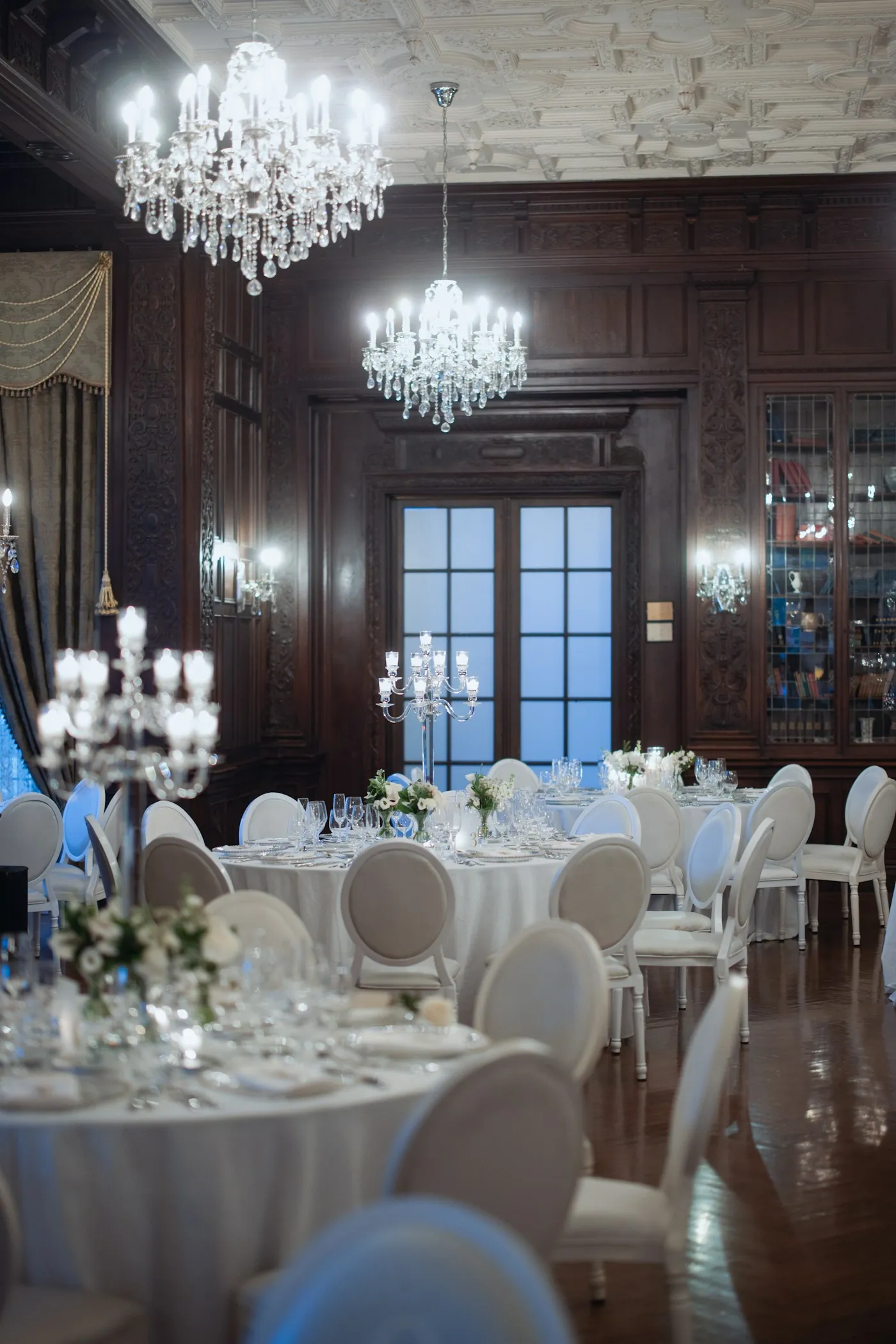 Salón elegante preparado con mesas redondas y candelabros